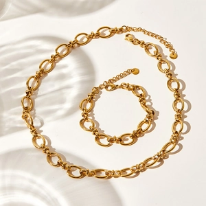 Minimalist gold-plated stainless steel chain necklace and bracelet set on a white surface