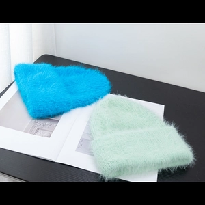Detail of soft fuzzy knit beanies in vibrant blue and mint green for winter warmth