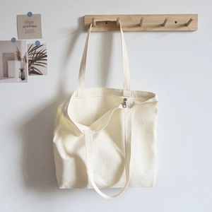 Minimalist beige canvas tote bag with silk-screen pattern hanging on a wooden hook