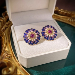 Detailed macro of vintage flower earring with blue enamel and faux pearls in box