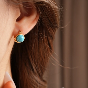 Gros plan détaillé de boucles d'oreilles vintage dorées avec résine turquoise ronde