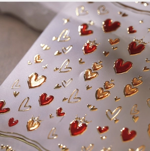 Close-up of luxury red and gold heart nail stickers with crown and star details