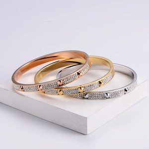 Three-piece stack of gold, silver, and rose gold nail bracelets with crystal inlay