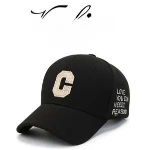 Detail of black baseball cap featuring beige embroidered C letter and side slogan