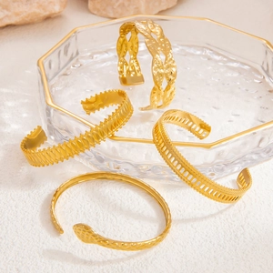 Detail of four 18K gold plated stainless steel bangles with Roman and textured designs