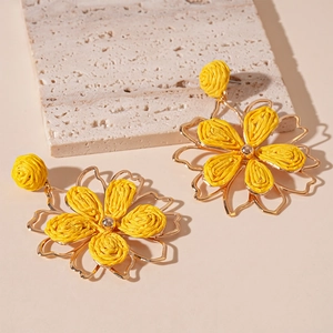 Detalle de los pendientes de rafia amarilla con pétalos de metal dorado elegante