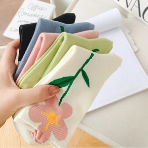 Five pairs of colorful crew socks with embroidered floral tulip patterns in a soft home setting
