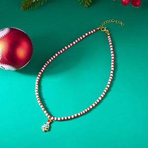 Detailed close-up of beaded Christmas tree necklace with festive ornaments on green background