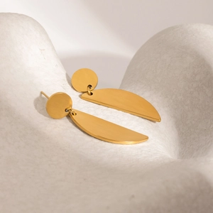 Close-up of golden geometric earrings with a brushed metal crescent moon texture