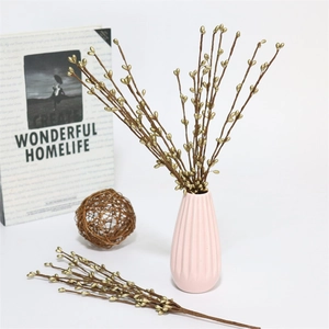 Golden artificial Christmas berry branches in a ceramic vase for festive home decoration