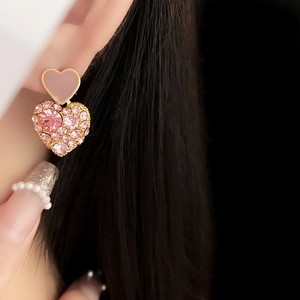 Detail of pink enamel and sparkling rhinestone heart earrings worn by a model