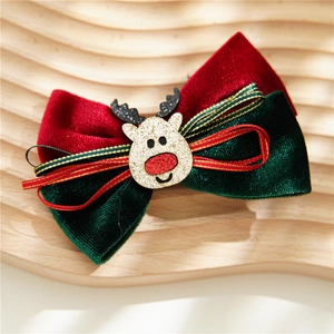 Close-up of a festive red and green velvet bow hairpin with a glittery reindeer center