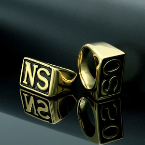 Close-up of golden stainless steel signet ring featuring engraved letters on square face