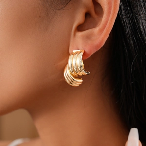 Close-up of a model wearing a triple-layered gold C-shaped metal earring for women