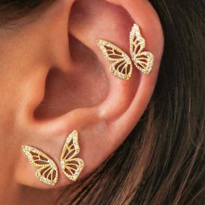 Macro shot of gold butterfly stud earrings with sparkling diamonds on a model's ear