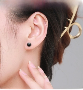Close-up of minimalist black agate stud earring with silver bezel on female model's ear