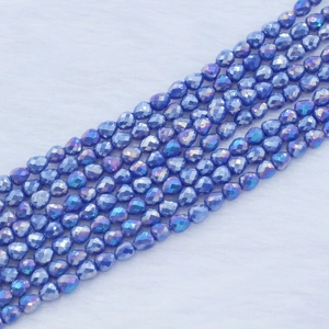 Macro view of blue faceted heart-shaped crystal beads with iridescent coating for DIY jewelry
