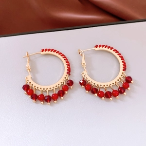 Detail of red beaded glass fringe and gold metal ring in a retro ethnic style earring