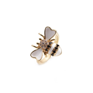 Macro shot of 18K gold bee ring featuring white heart wings and black zircon details