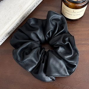 Chouchou rétro français en cuir noir sur un bureau en bois avec une bougie