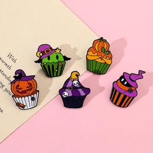 Close-up of five Halloween cupcake enamel pins featuring pumpkin, skull and bat designs