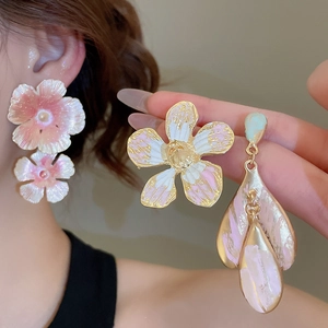 Detail of floral enamel earrings with pearls and gold trim on female model