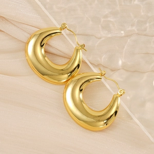 Detailed view of polished gold chunky C-shape hoop earrings on elegant silk background
