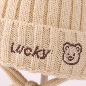 Children's winter beige knitted hat featuring LUCKY embroidery and a cute bear patch