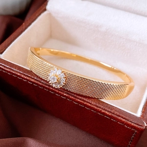 Detailed macro view of 18K gold plated woven texture bracelet with flower zircon setting