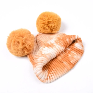 Dettaglio del cappello in maglia tie-dye arancione con due pompon in pelliccia sintetica