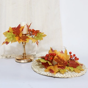 Macro detail of autumn candle ring with faux maple leaves and vibrant red berries