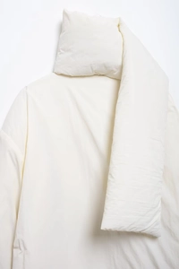 Detail der weißen Steppjacke mit Schalkragen zeigt weiche Stofftextur und Wattierung