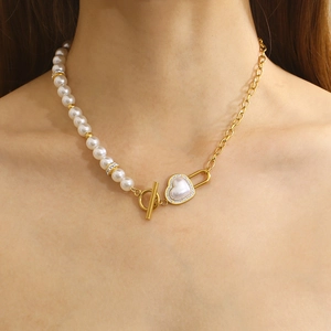 Close-up of asymmetrical gold necklace with pearls and a shell heart-shaped OT buckle