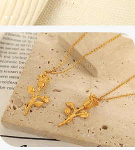 Macro shot of gold rose pendant showing detailed flower petals and delicate chain