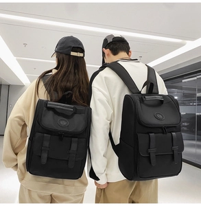 Detail of couple wearing black nylon backpacks with buckle straps in a bright indoor setting
