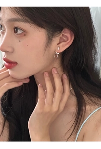 Dettaglio di orecchini a perno a forma di fiocco argento indossati da una modella