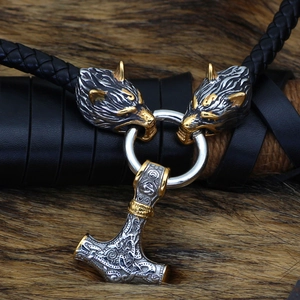 Close-up of Mjolnir pendant with wolf heads and black leather cord on fur background
