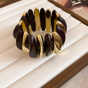 Detail view of rhombic brown matte and gold metal segments on stretch bracelet