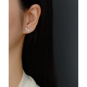 Macro detail of silver bow stud earring with sparkling zircon on model ear