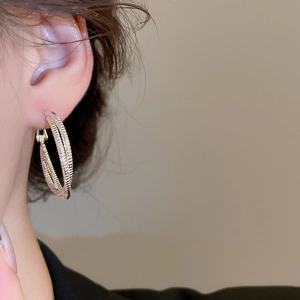 Detail view of silver textured multi-layered hoop earrings worn on a model's ear