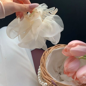 Close-up of beige organza flower hair claw clip with delicate layered mesh fabric texture