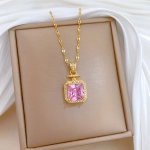 Gros plan d'un collier doré avec pendentif flacon en pierre rose sur fond de soie