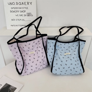 Dettaglio di borse tote viola chiaro e blu con stampe di fiocchi neri e tracolle comode