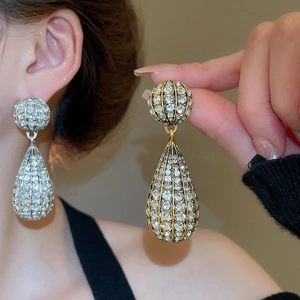 Close-up of sparkling full-rhinestone teardrop earrings in gold and silver finishes