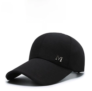 Detail of a black canvas baseball cap featuring a silver metallic M letter emblem