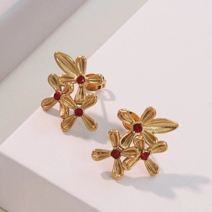 Elegant gold earrings with three floral clusters and red gemstones on white background