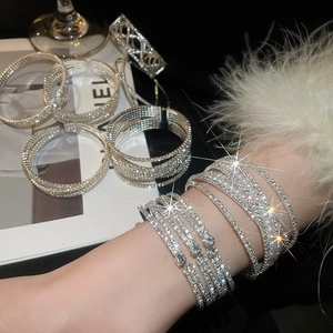 Close-up of sparkling artificial pearl and rhinestone crossover bracelets in silver finish