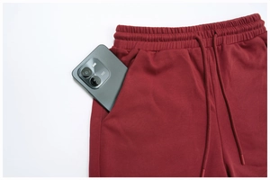 Detail view of deep red athletic shorts showing deep side pocket and cotton fabric texture