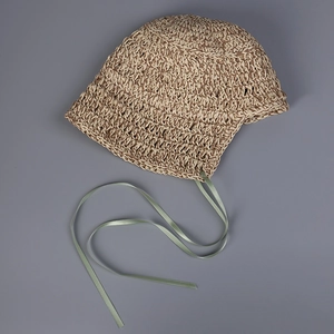 Detailed texture of handmade straw bucket hat with delicate green silk ribbon ties