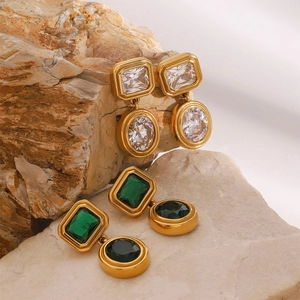 Detail of vintage gold-plated stud earrings with white and green zircon stones on stone